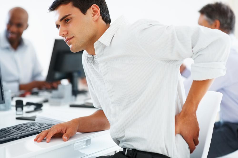 man at desk with back pain before seeing a Clayton Chiropractor
